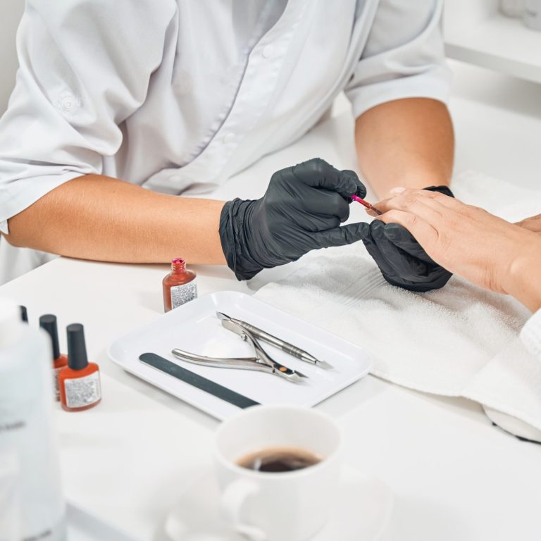 Attentive beautician applies new layer of nail polish