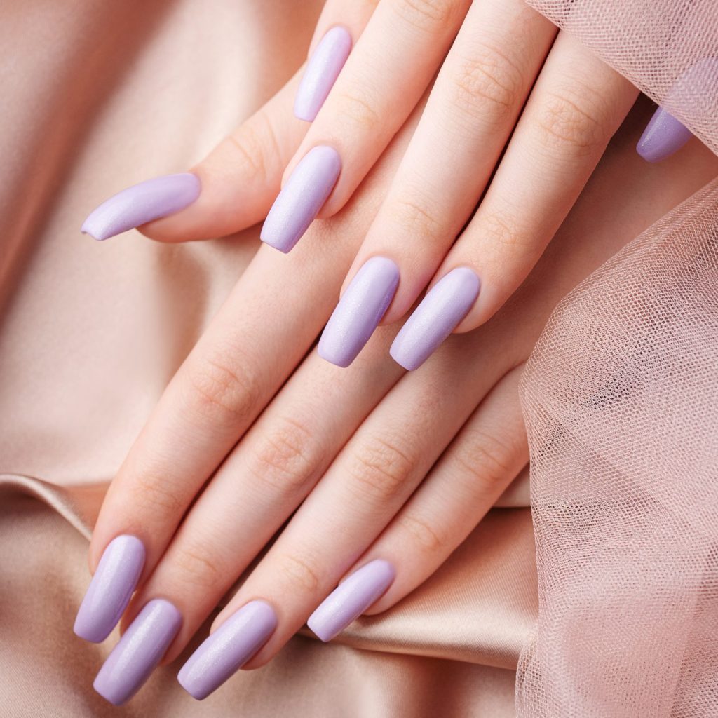 Girl's hands with a soft purple manicure.